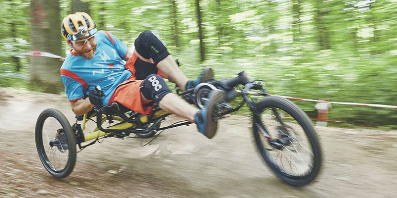 Man riding a KETTWIESEL CROSS recumbent trike on a mountain bike trail