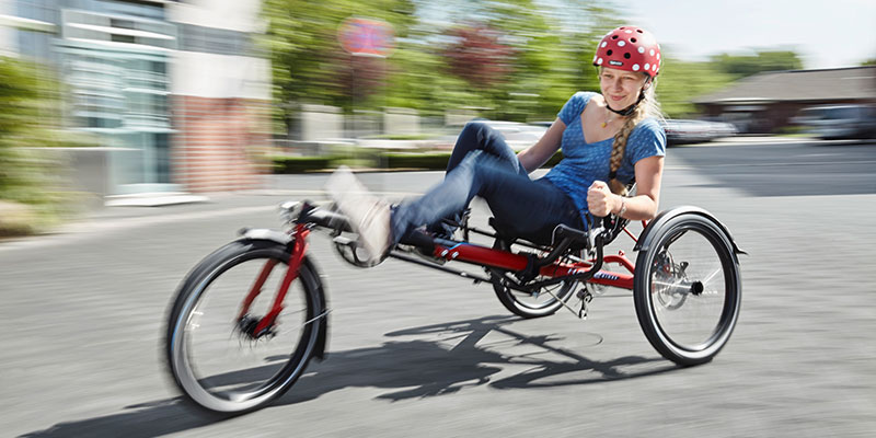 Smiling woman riding into a corner with a KETTWIESEL MODULAR recumbent trike