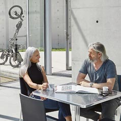 Couple sitting at a table with the KETTWIESEL EVO STEPS parked upright in the background