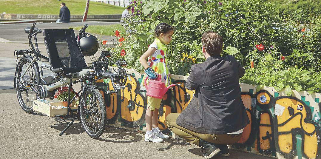 Father and daughter tending a garden using a HASE PINO tandem cargo bike to carry supplies