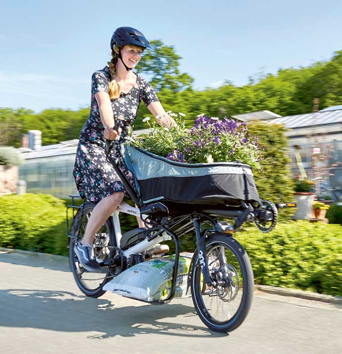 Woman riding a Hase Pino STEPS with the porter bag full of flowers
