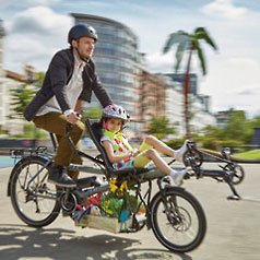 Man and child riding a tandem Pino Steps bike