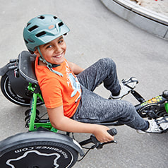 Boy riding a TRETS recumbent trike, looking up and smiling