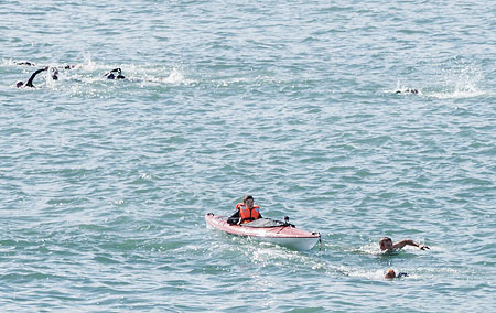 Triathlon swimmer followed by a kayaker