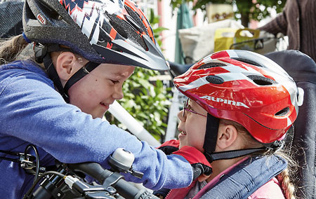 Two children in bike helmets smiling at each other
